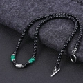 Detail of beaded necklace featuring black stones and green malachite with silver T-bar clasp - Malachite