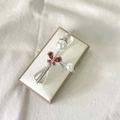 Silver butterfly bangle with red gemstone and white pearls on a beige display stand - Red