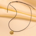Gros plan d'un pendentif coquillage doré avec cordon noir réglable sur soie beige - Collier Pendentif Coquillage Cordon Noir (QYH6066) / Or