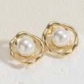 Detail van elegante goudkleurige golvende oorbellen met witte parels op witte steen - Enkele Parel U-Vorm Oorbellen