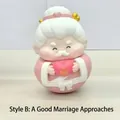 Cute elder doll ornament in pink robe holding a heart with a golden symbol - 3070 Love Figure with Heart