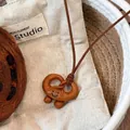 Macro di una graziosa collana con ciondolo a forma di pretzel sorridente e cordino - Pretzel Sorriso