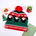 Detail view of colorful knitted LED Christmas hat featuring Santa Claus patterns and switch - Red Green Black Santa Heads