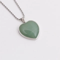 Green heart crystal pendant with silver twisted chain on white background - Green