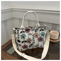 Detailansicht der beigefarbenen Canvas-Tasche mit Blumenmuster und verstellbarem Gurt - Dunkles Blumenmuster