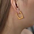 Vintage U-shape geometric gold earrings with textured surface worn by model - Gold