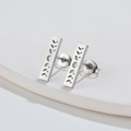 Detailed view of silver rectangular stud earrings with moon phase engraving on ceramic tray - 530 Moon Phases Bar - Steel