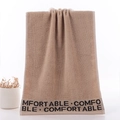 Thick beige cotton towel featuring comfortable lettering and soft loop texture - Alphabet Brown