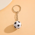 Miniature black and white soccer ball keychain with silver metal ring on orange backdrop - White K Keychain Wg-0789