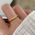 Detailansicht eines goldenen unregelmäßigen Rings mit Je t'aime Gravur am Finger - US 5 / Gold