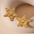 Macro shot of gold starfish earrings with textured hammered finish on white ceramic - Gold Hammered Sea Star (Steel Pin) / Gold