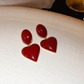 Detailed macro shot of vintage burgundy heart earrings with polished gold metallic frame - Red