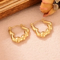 Gros plan de boucles d'oreilles dorées torsadées sur cadre bois et fleurs séchées - Style Forme de Vague (WGXA0035055017B)