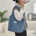 Lifestyle-Foto der großen Denim-Einkaufstasche mit weißen Schleifen und Schultergurt - Dunkelblau