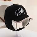 Detailansicht der gesteppten Wintermütze mit Kelly-Stickerei und weißem Lammfellfutter - Einheitsgröße / Schwarz