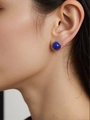Macro view of a gold-framed round dark blue lapis lazuli stud earring worn by a model - Natural Lapis Lazuli Round Gold 8mm