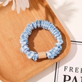 Close-up of blue and white checkered fabric scrunchie with a rectangle buckle on a wooden tray - Satin Blue White Plaid