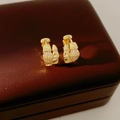 Vista macro di orecchini a serpente placcati in oro 14K con zirconi su pelle marrone - Oro