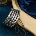 Detailed view of multilayer silver-black snake-shaped coiled bracelet on blue velvet - Black & Silver Mixed Closed Style