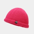 Détail d'un bonnet en maille rose vif avec un écusson carré noir et logo lettre N - Rose rouge