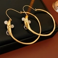Detail von goldenen matten Creolen mit Strasskugeln auf einem schwarzen Lederetui - Hoop Earrings / Gold