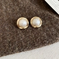 Detailed close-up of gold-plated geometric pearl stud earrings on soft cashmere fabric - Beige Wavy (Gold Plated Silver Pin)