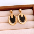 Detailed macro view of handmade gold-plated oval resin earrings with geometric design - Gold-Black