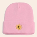 Detailed view of pink knitted beanie featuring sun and moon embroidery on folded brim - Pink