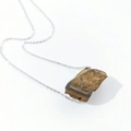Macro detail of irregular raw tiger eye stone pendant on a silver thin chain necklace - Tiger Eye