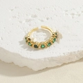 Adjustable golden ring with seven green round zircon stones on a white stone background - Adjustable Open / Green