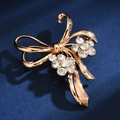 Macro shot of elegant golden bow brooch with sparkling rhinestones on dark blue velvet - AB Crystal Bowknot