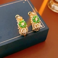Macro detail of vintage gold hoop earrings with green beads and pearls on jewelry box - Gold