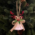 White Christmas bell ornament with burlap bow and red berries hanging on a festive tree - White Wind Bell