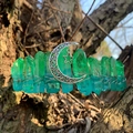 Macro detail of raw green crystal crown with silver moon and star charms on bark - Green Blue