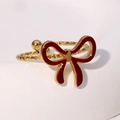 Detailed macro view of a vintage gold bow ring with red enamel and textured band - Burgundy