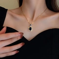 Dettaglio di una lussuosa collana dorata con pietra rettangolare blu indossata da modella - Collana di Smeraldo / Oro