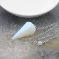 Ciondolo in opale esagonale con catena argentata esposto su una base di pietra naturale - Opalite