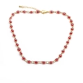 Détail de la chevillère dorée ornée de breloques œil grec en émail rouge sur fond blanc - Collier Rouge
