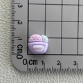 Makroaufnahme eines 1cm Mini-Harz-Cupcakes mit Sweet-Schriftzug auf einer Messskala - Violetter süßer Keks