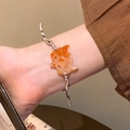Elegant beaded bracelet with orange carved charm and woven silver brown strap on wrist - Brown/Fox Shape