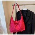 Detail einer roten Wildledertasche mit Kordelzugschleife auf schwarzem Blazer - Burgunderrot