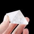 Hand die een heldere natuurlijke witte kwartspiramide vasthoudt met ijsbarsttexturen - 5cm