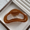 Detail of amber jelly hair claw clip with cutout design on a wooden display - Fruit Coffee
