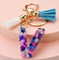 Detailed view of resin letter V keychain with colorful stones and soft blue white tassels - Letter V