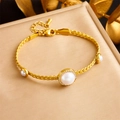 Détail d'un bracelet doré avec perles et diamants sur un support d'exposition beige - B1430
