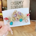 Golden butterfly hair clip with colorful crystals shown in a hand-held variant view - Colorful