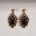 Macro detail of retro gold earrings featuring black teardrop stones and intricate carvings - Silver Needle - Black Earrings