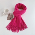 Detail shot of a soft fuchsia fringed scarf knotted next to a ceramic mug on a white table - Regular Fit / Pink