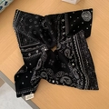 Bovenaanzicht van een zwart-witte bandana met paisleyprint op een houten achtergrond - Zwarte haarelastiek