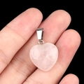 Pink quartz heart pendant 16mm with silver clasp held by hand on black background - Rose Quartz
